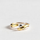 Siena Two-Tone Twist Ring in gold and silver tones on a light grey background