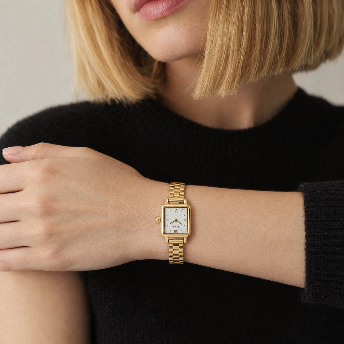 CLARA Square Bracelet Watch worn on the left wrist of a blonde woman wearing a black knit top