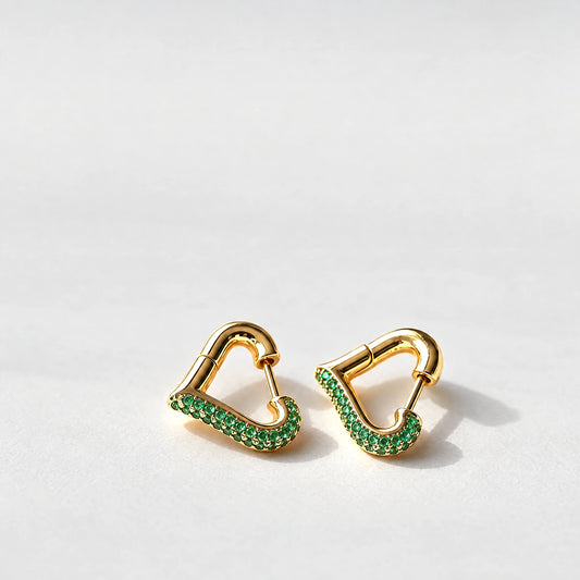 Gold Cora Crystal Heart Hoop Earrings with green crystals on a light grey background