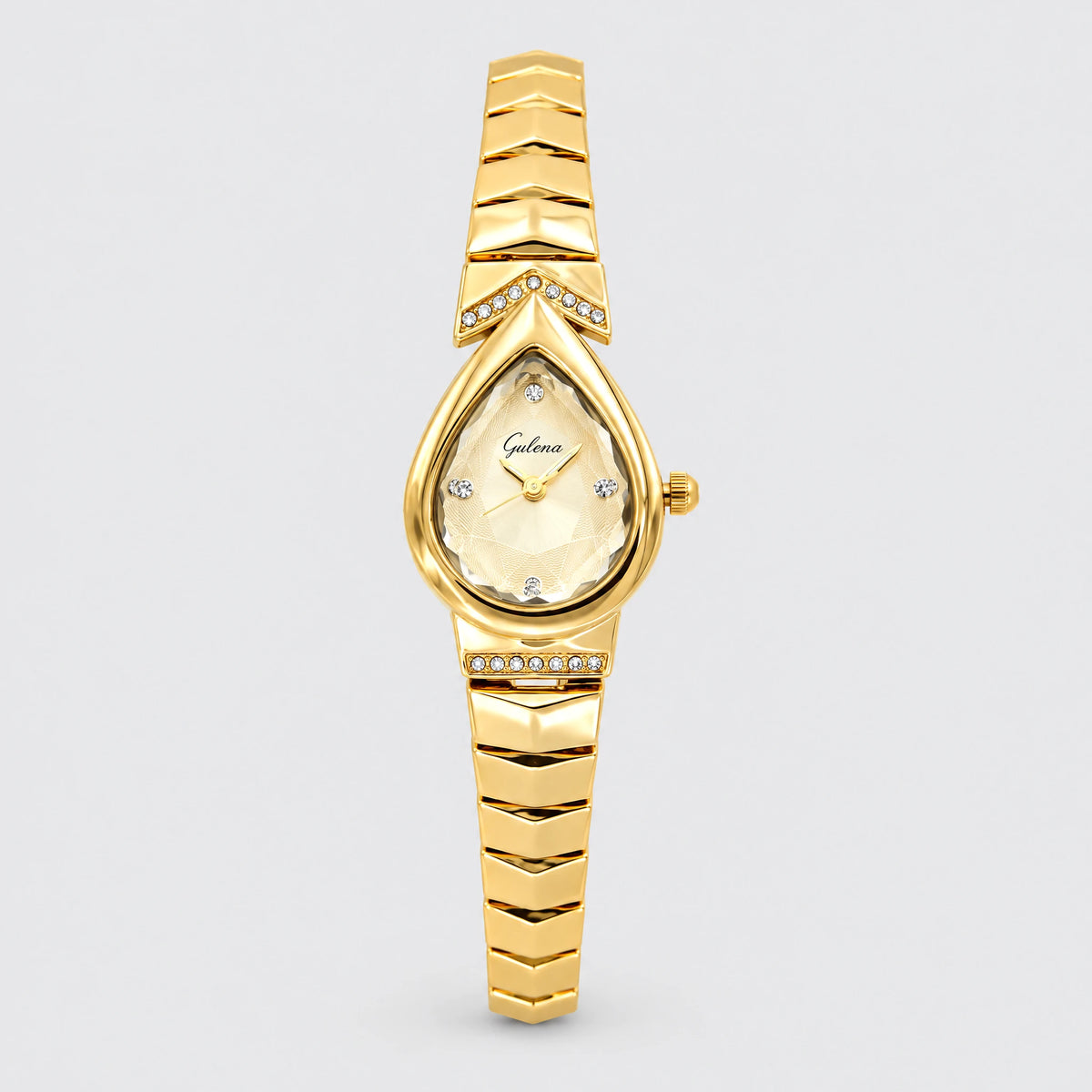 ISLA Teardrop Bracelet Watch in gold tone with a faceted teardrop dial and crystal-set chevron plates on a light grey background