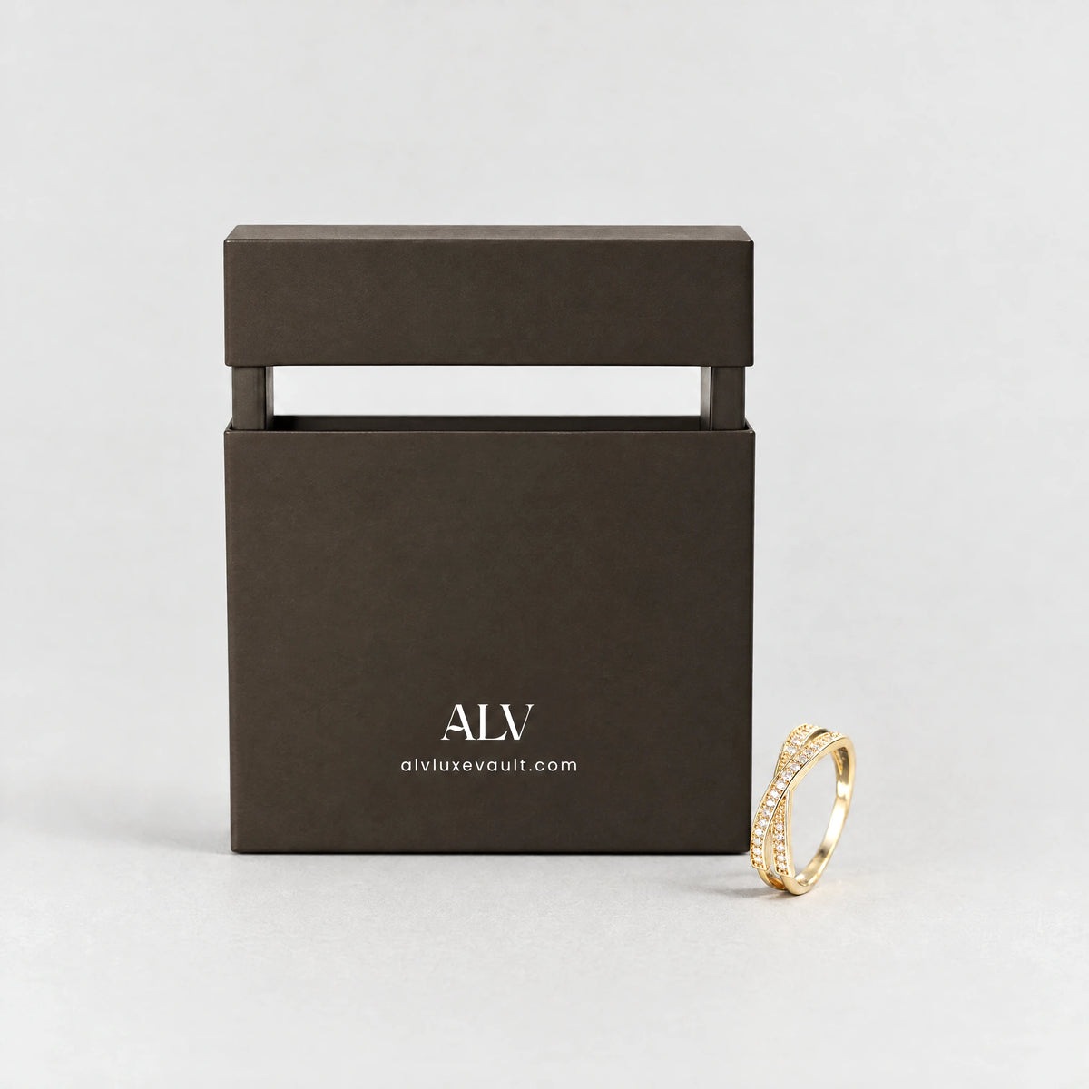 Gold Ivy Crossover Crystal Ring beside the ALV gift box