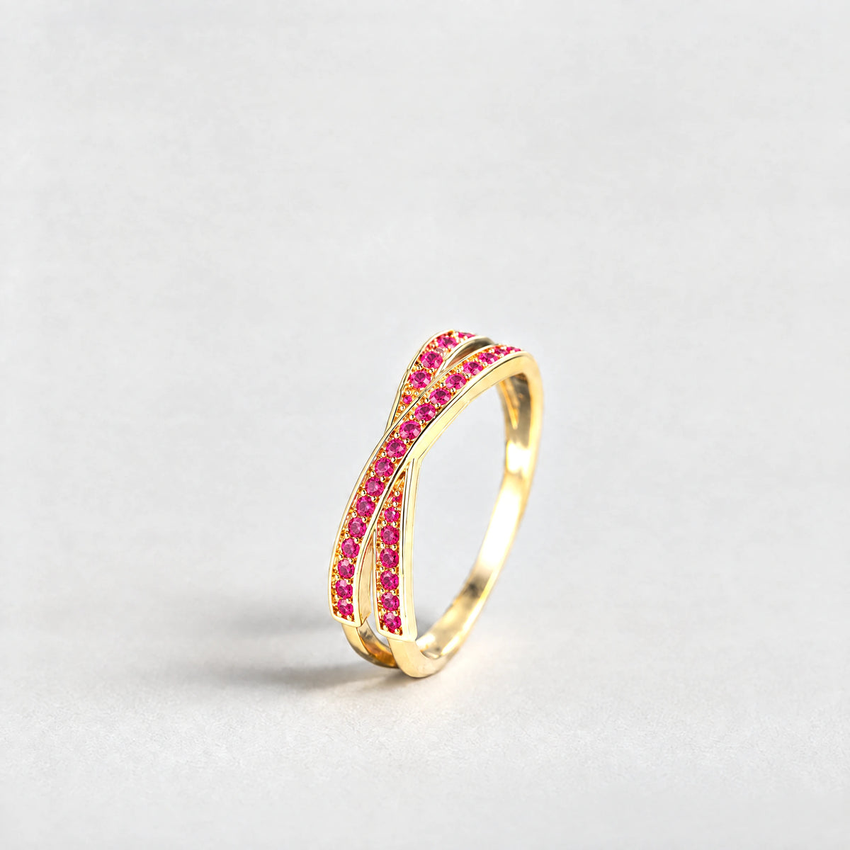 Gold Ivy Crossover Crystal Ring with pink crystals on a light grey background