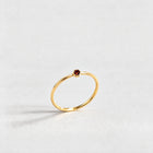 Gold Lena Birthstone Ring with garnet red January birthstone-color crystal on a light grey background