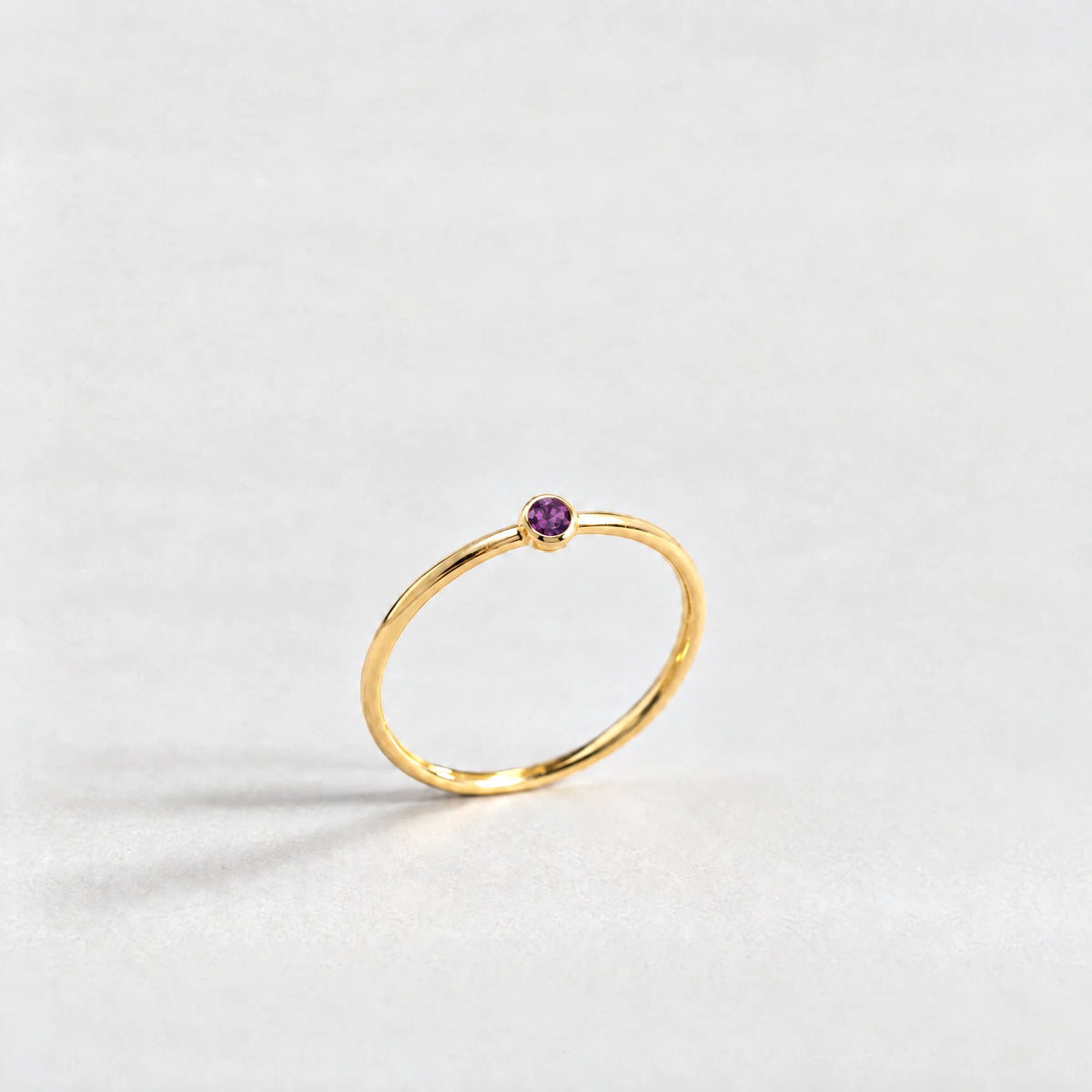 Gold Lena Birthstone Ring with alexandrite plum June birthstone-color crystal on a light grey background