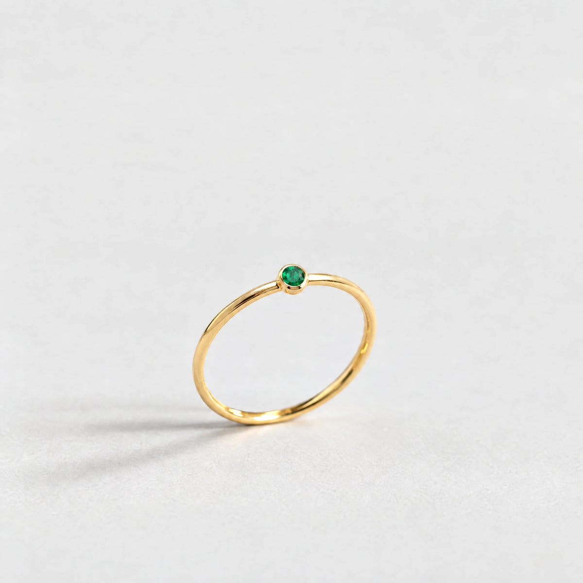 Gold Lena Birthstone Ring with emerald green May birthstone-color crystal on a light grey background
