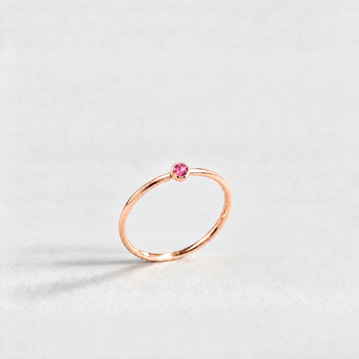 Rose gold Lena Birthstone Ring with ruby rose July birthstone-color crystal on a light grey background