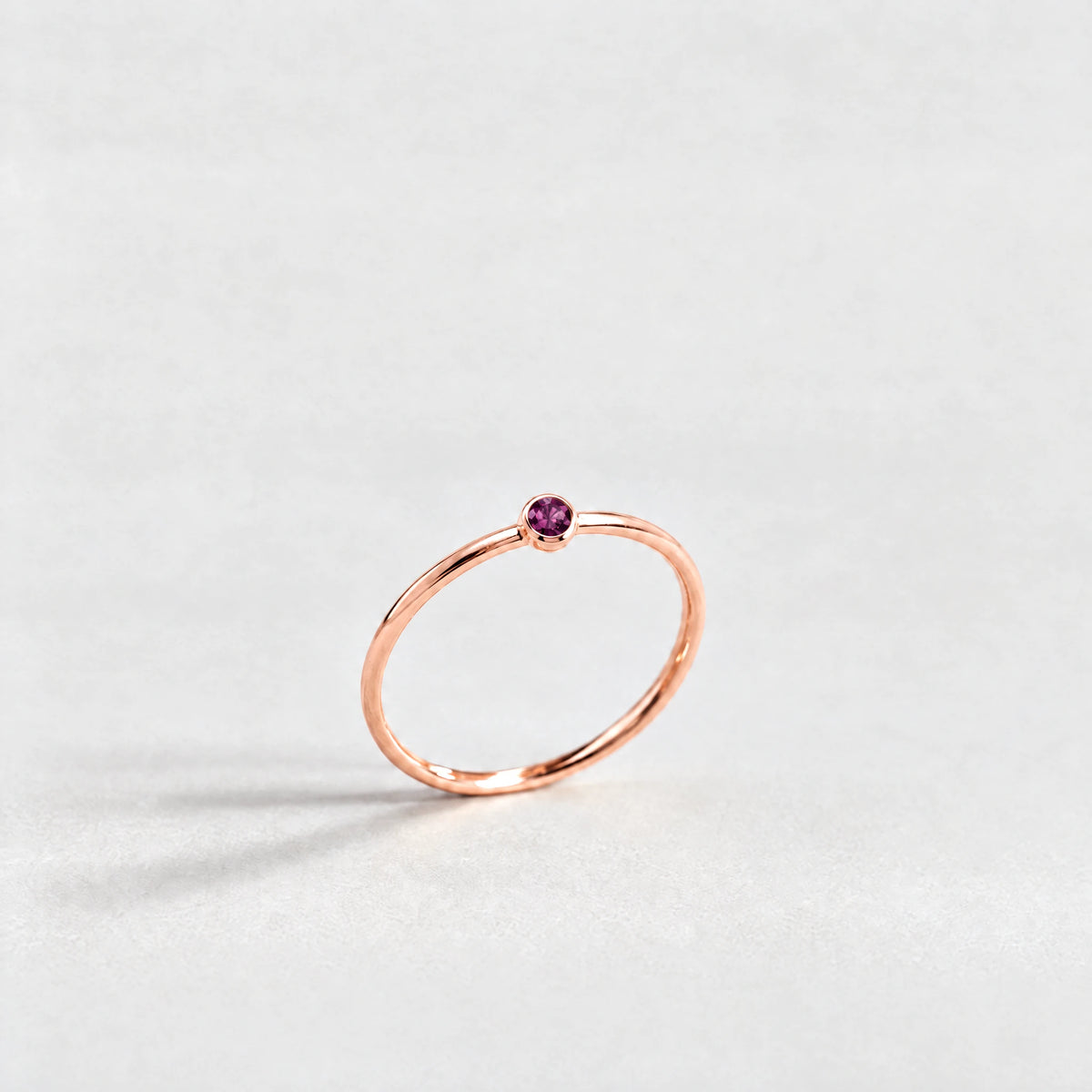 Rose gold Lena Birthstone Ring with alexandrite plum June birthstone-color crystal on a light grey background