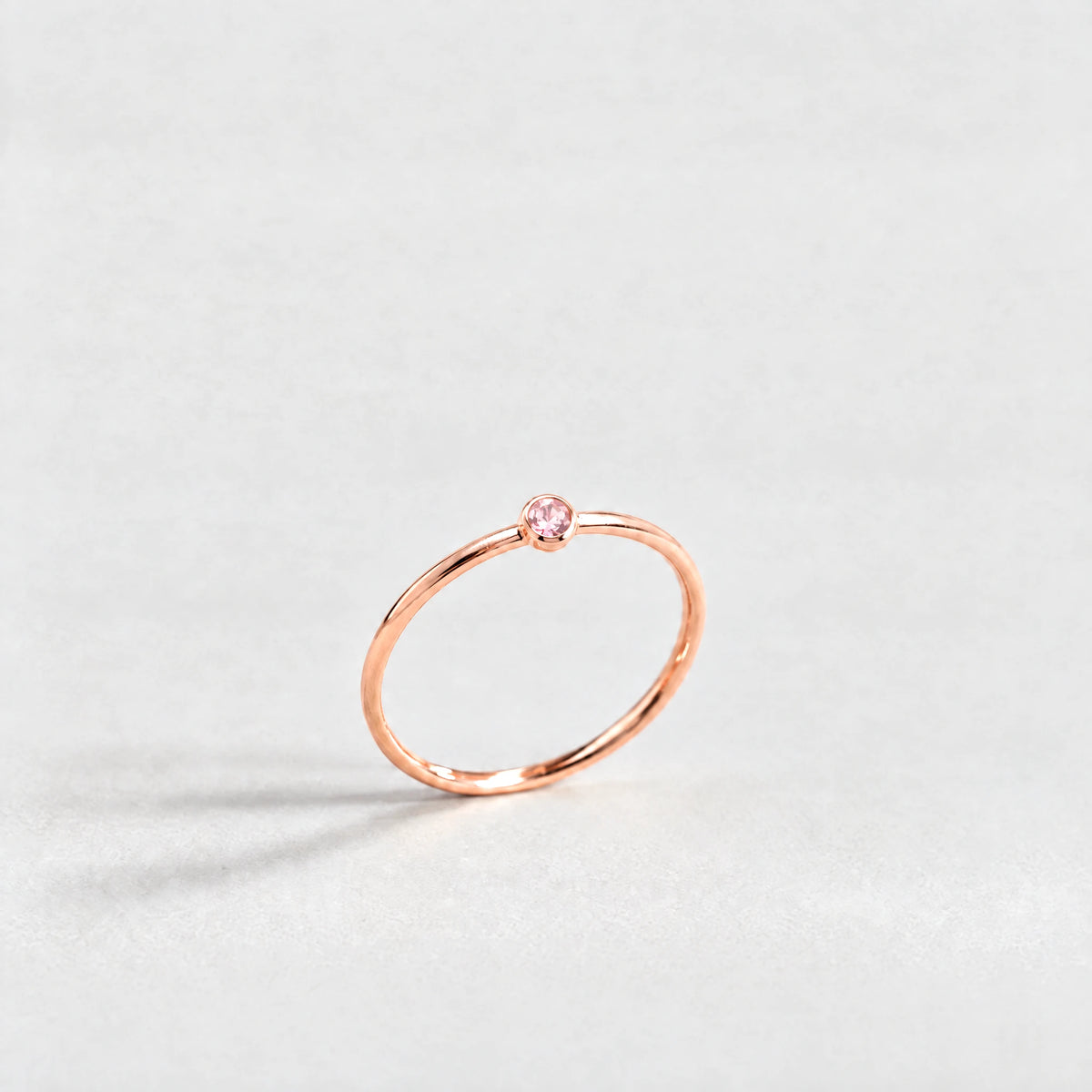 Rose gold Lena Birthstone Ring with tourmaline pink October birthstone-color crystal on a light grey background