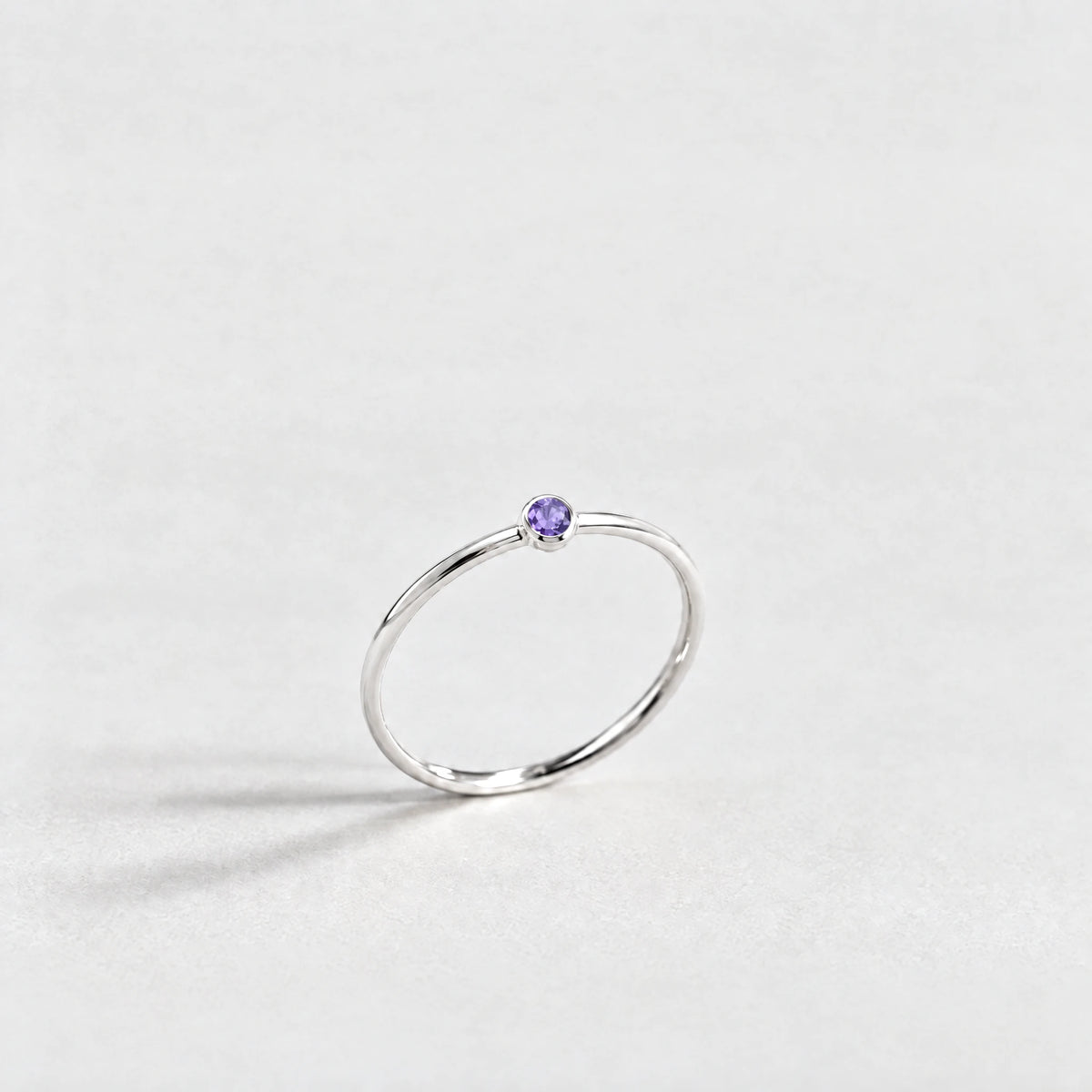 Silver Lena Birthstone Ring with amethyst violet February birthstone-color crystal on a light grey background