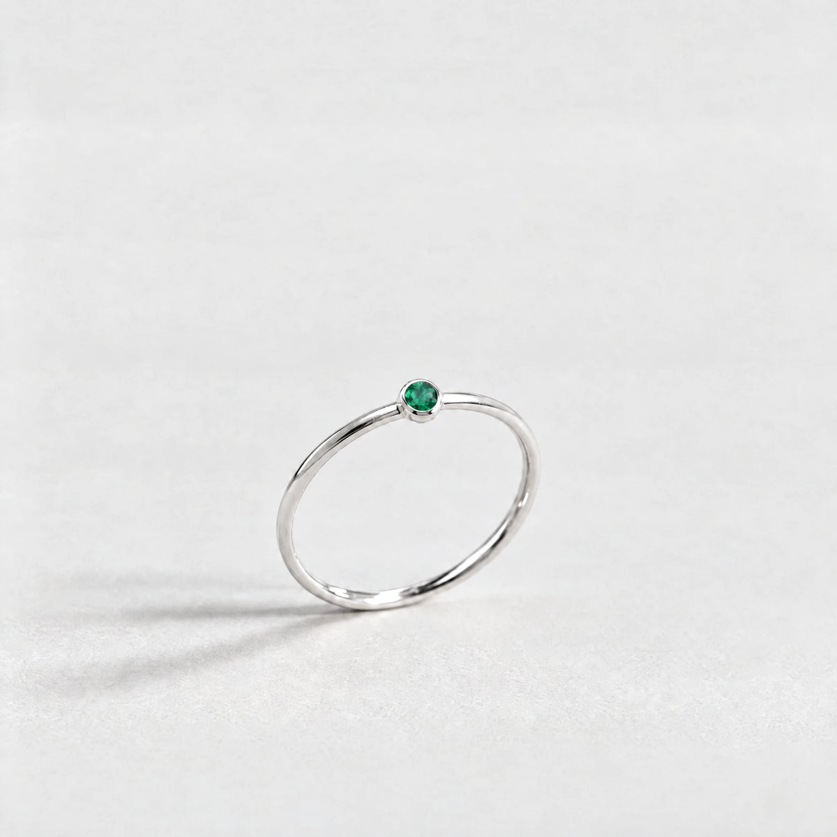 Silver Lena Birthstone Ring with emerald green May birthstone-color crystal on a light grey background