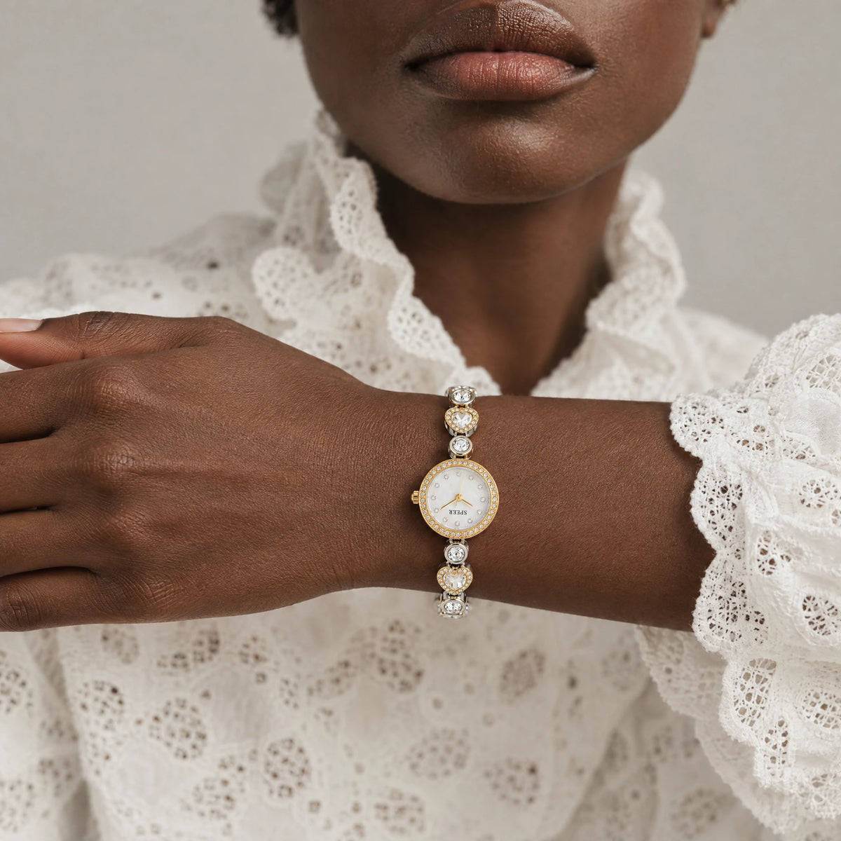 LOLA Heart Bracelet Watch worn on the left wrist of a woman in a white lace blouse