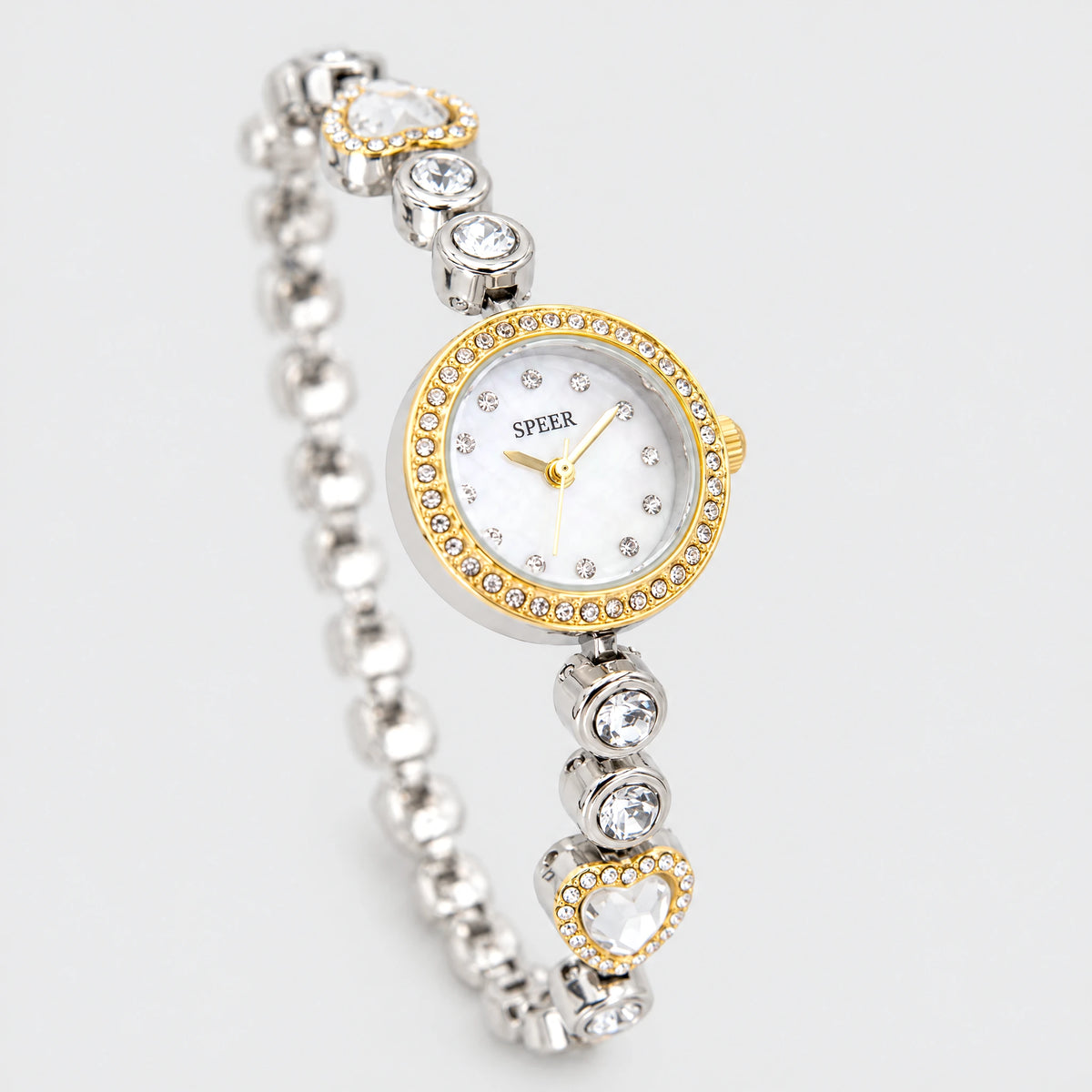 LOLA Heart Bracelet Watch in two-tone gold and silver with a crystal-rimmed dial and heart links on a light grey background