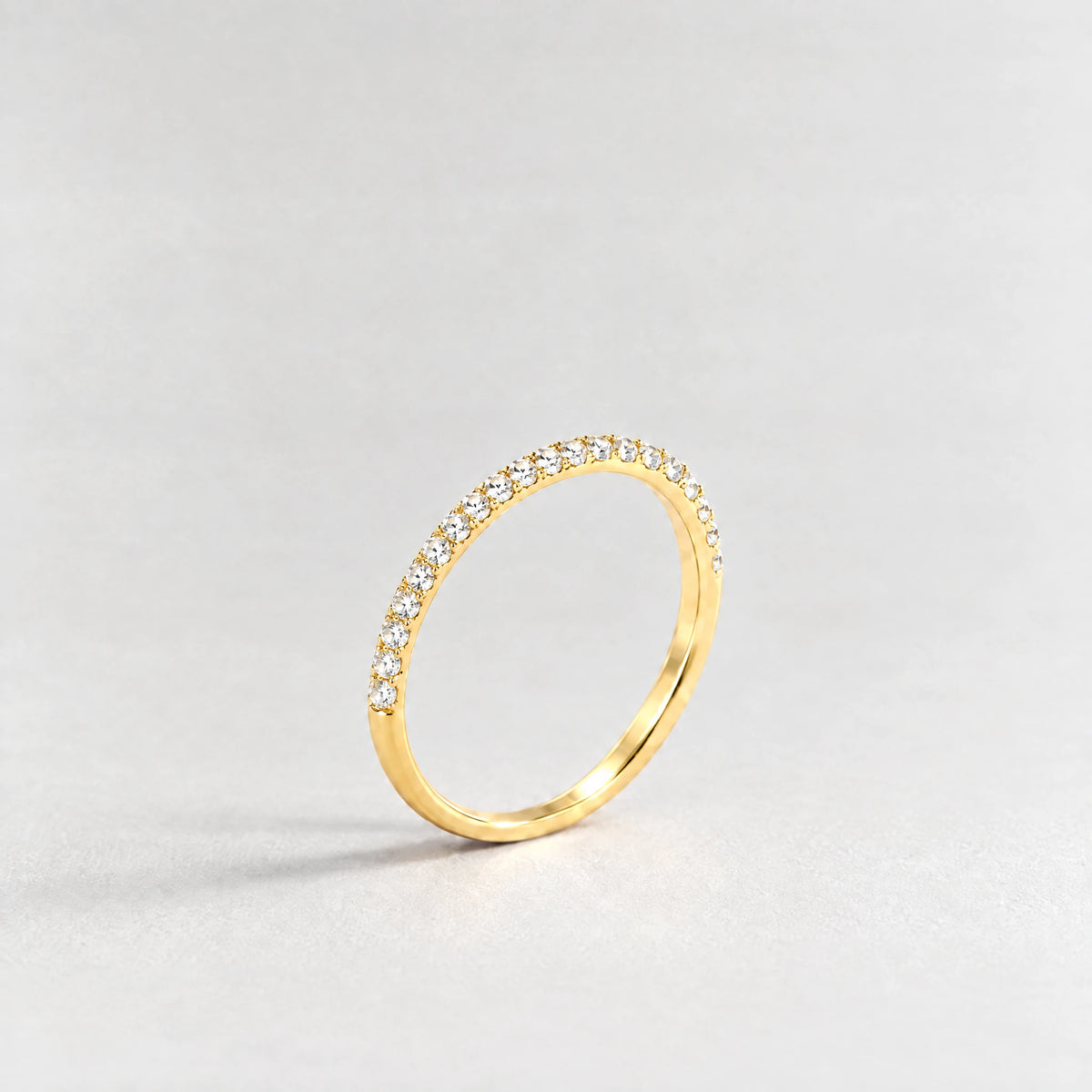Gold Nora Birthstone Stacking Ring with clear crystal April birthstone-color crystals on a light grey background