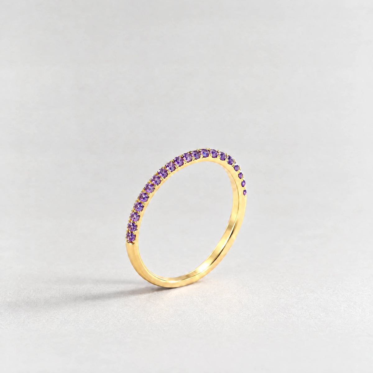 Gold Nora Birthstone Stacking Ring with amethyst violet February birthstone-color crystals on a light grey background
