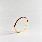 Gold Nora Birthstone Stacking Ring with garnet red January birthstone-color crystals on a light grey background