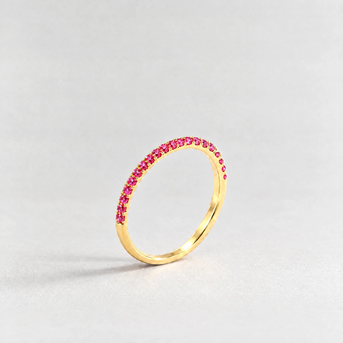 Gold Nora Birthstone Stacking Ring with ruby rose July birthstone-color crystals on a light grey background