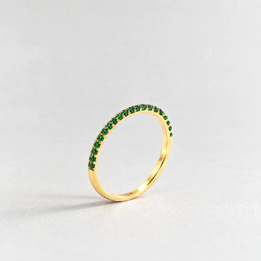 Gold Nora Birthstone Stacking Ring with emerald green May birthstone-color crystals on a light grey background