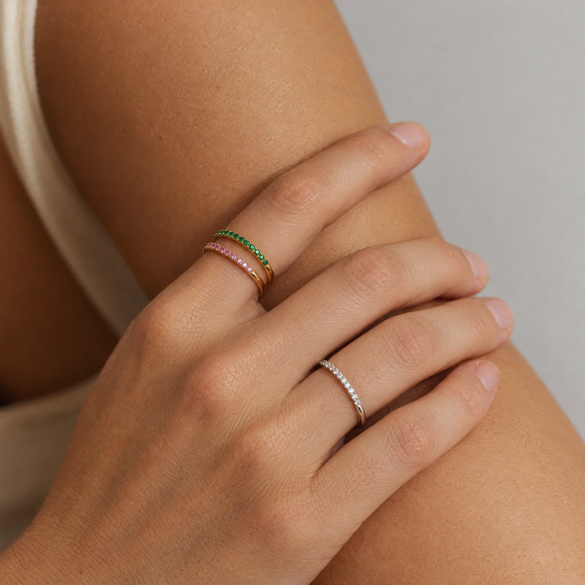 Hands resting on a bare arm wearing gold and silver Nora Birthstone Stacking Rings