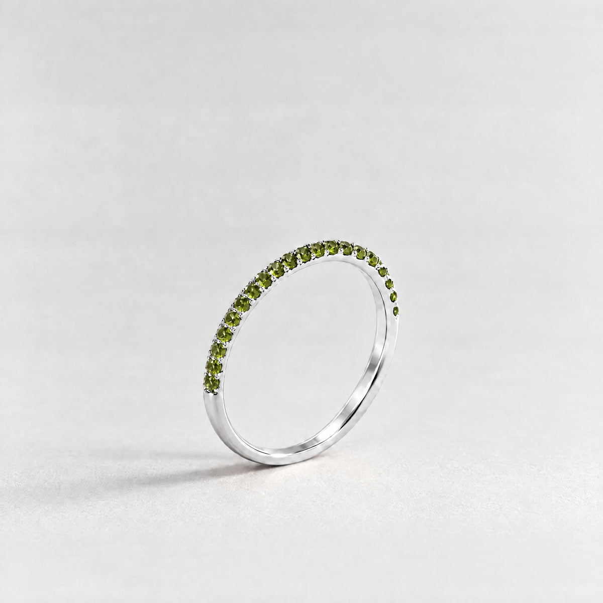 Silver Nora Birthstone Stacking Ring with peridot green August birthstone-color crystals on a light grey background