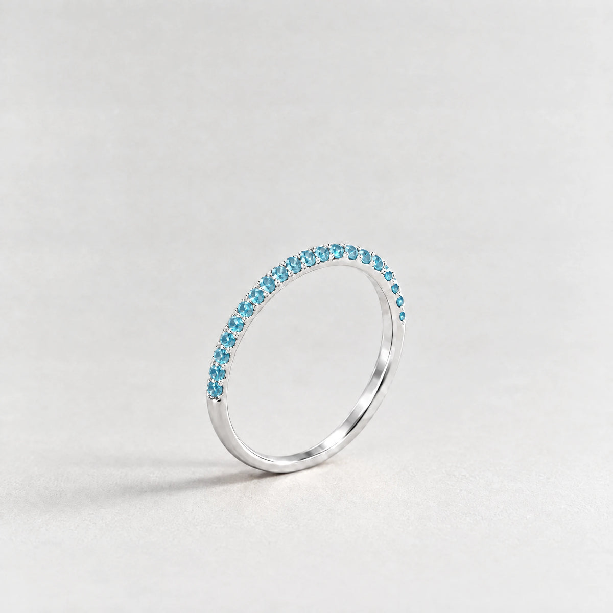 Silver Nora Birthstone Stacking Ring with topaz blue December birthstone-color crystals on a light grey background