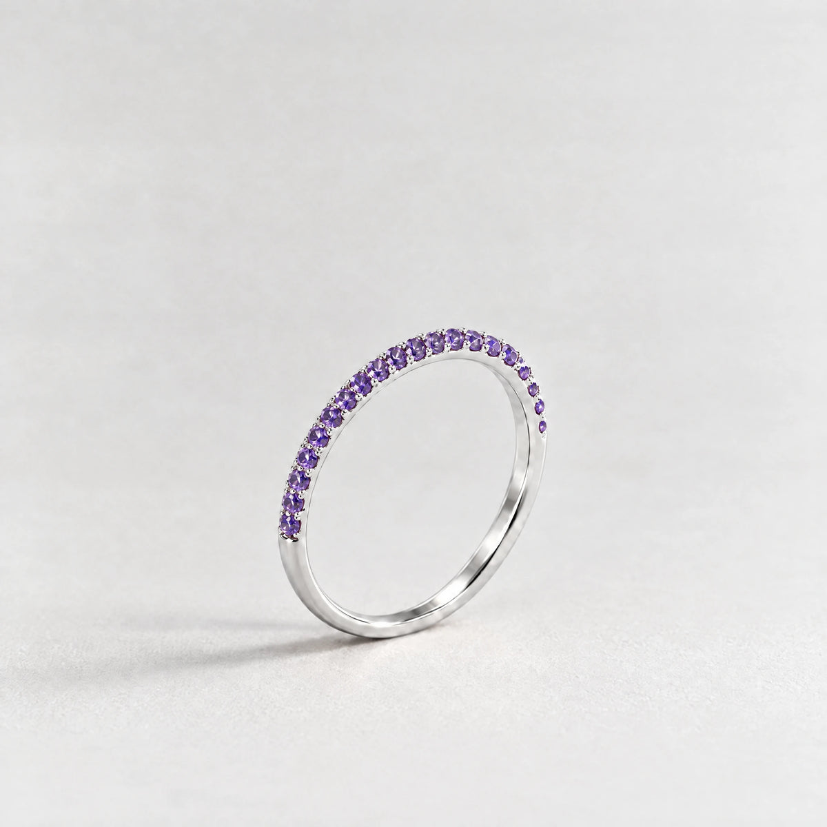 Silver Nora Birthstone Stacking Ring with amethyst violet February birthstone-color crystals on a light grey background