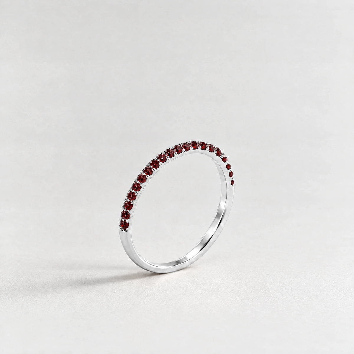 Silver Nora Birthstone Stacking Ring with garnet red January birthstone-color crystals on a light grey background