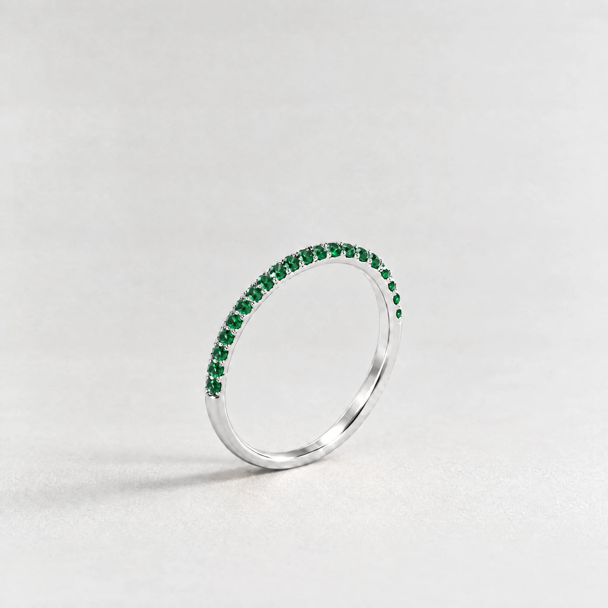 Silver Nora Birthstone Stacking Ring with emerald green May birthstone-color crystals on a light grey background