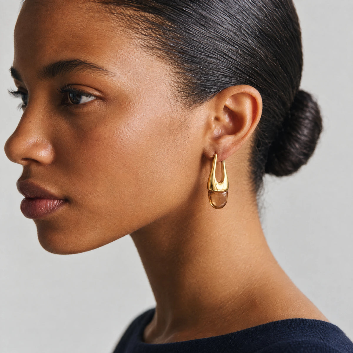 Woman with a low bun wearing a gold Pia U-Shape Hoop Earring