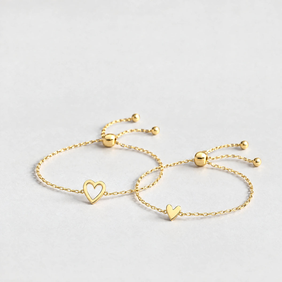 Gold Rosie Two Hearts Bracelet Set with an open heart and a small solid heart on a light grey background