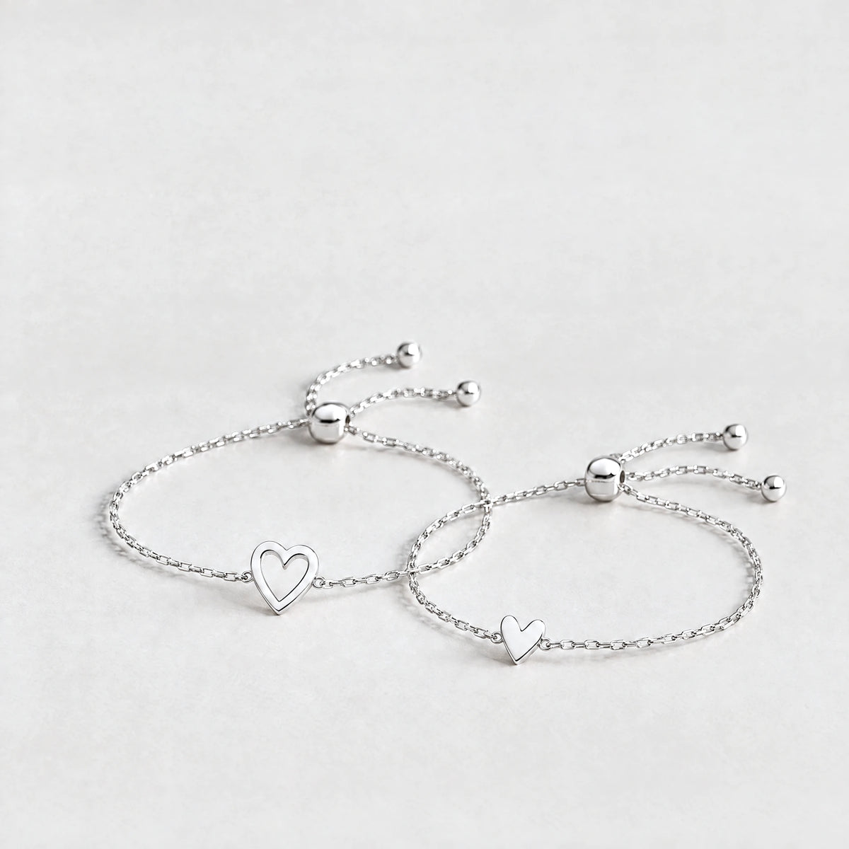 Silver Rosie Two Hearts Bracelet Set with an open heart and a small solid heart on a light grey background