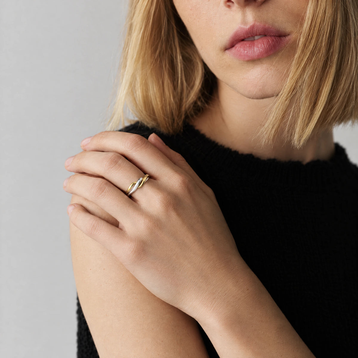 Blonde woman with her hand on her shoulder wearing the Siena Two-Tone Twist Ring