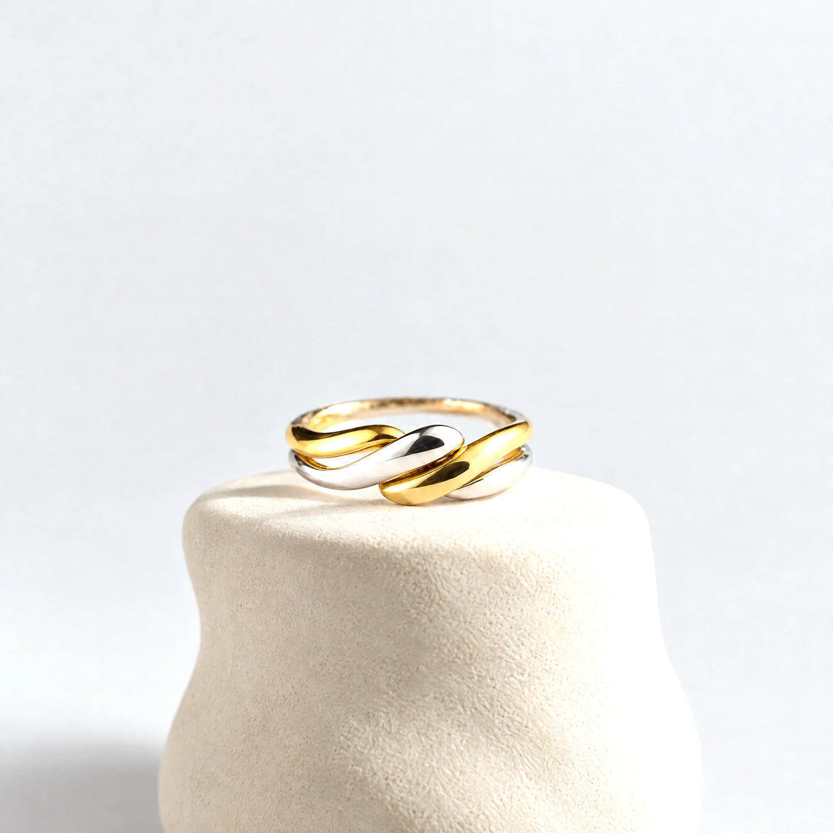 Siena Two-Tone Twist Ring on a cream clay pedestal