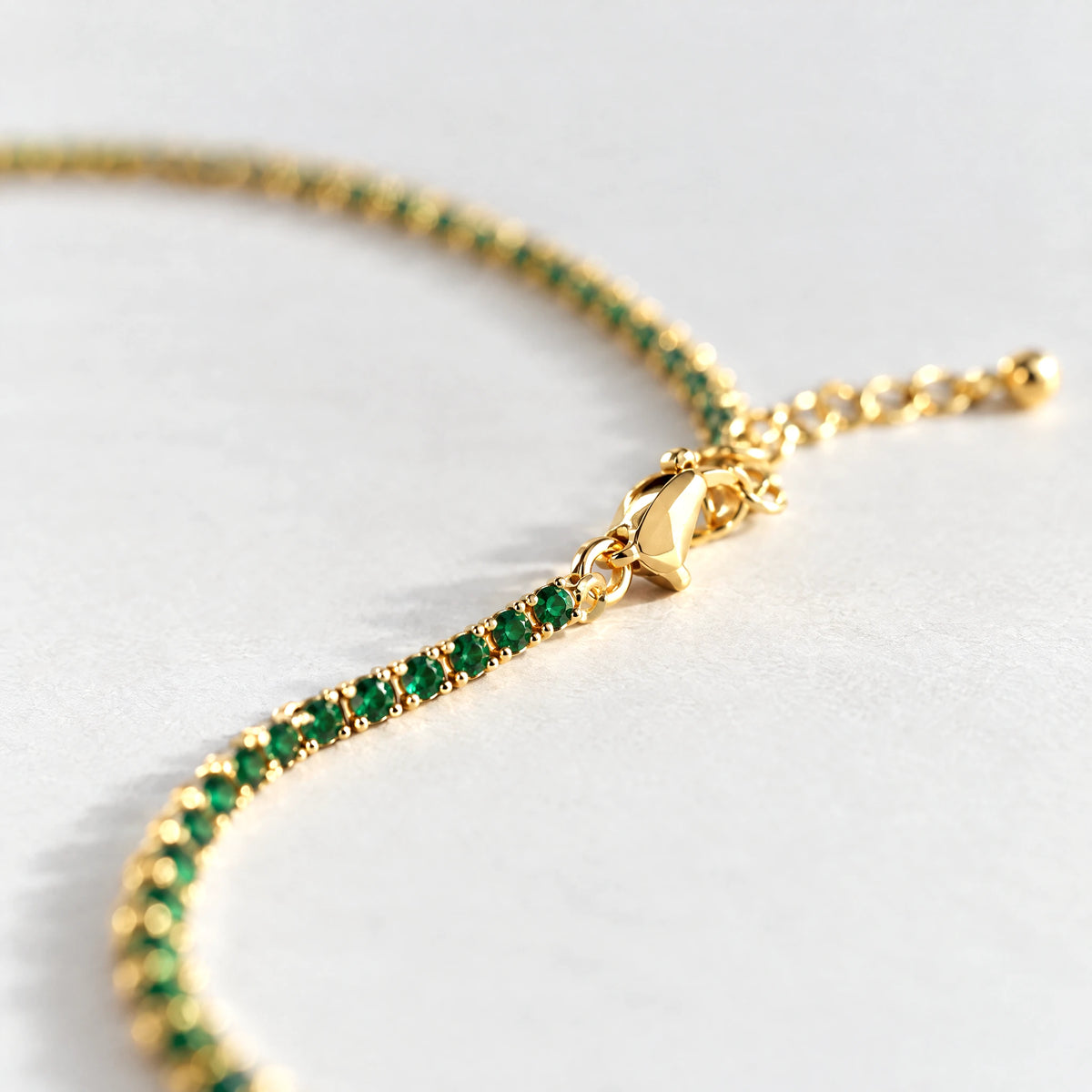 Close-up of the emerald green crystals and clasp on the gold Tessa Birthstone Tennis Necklace