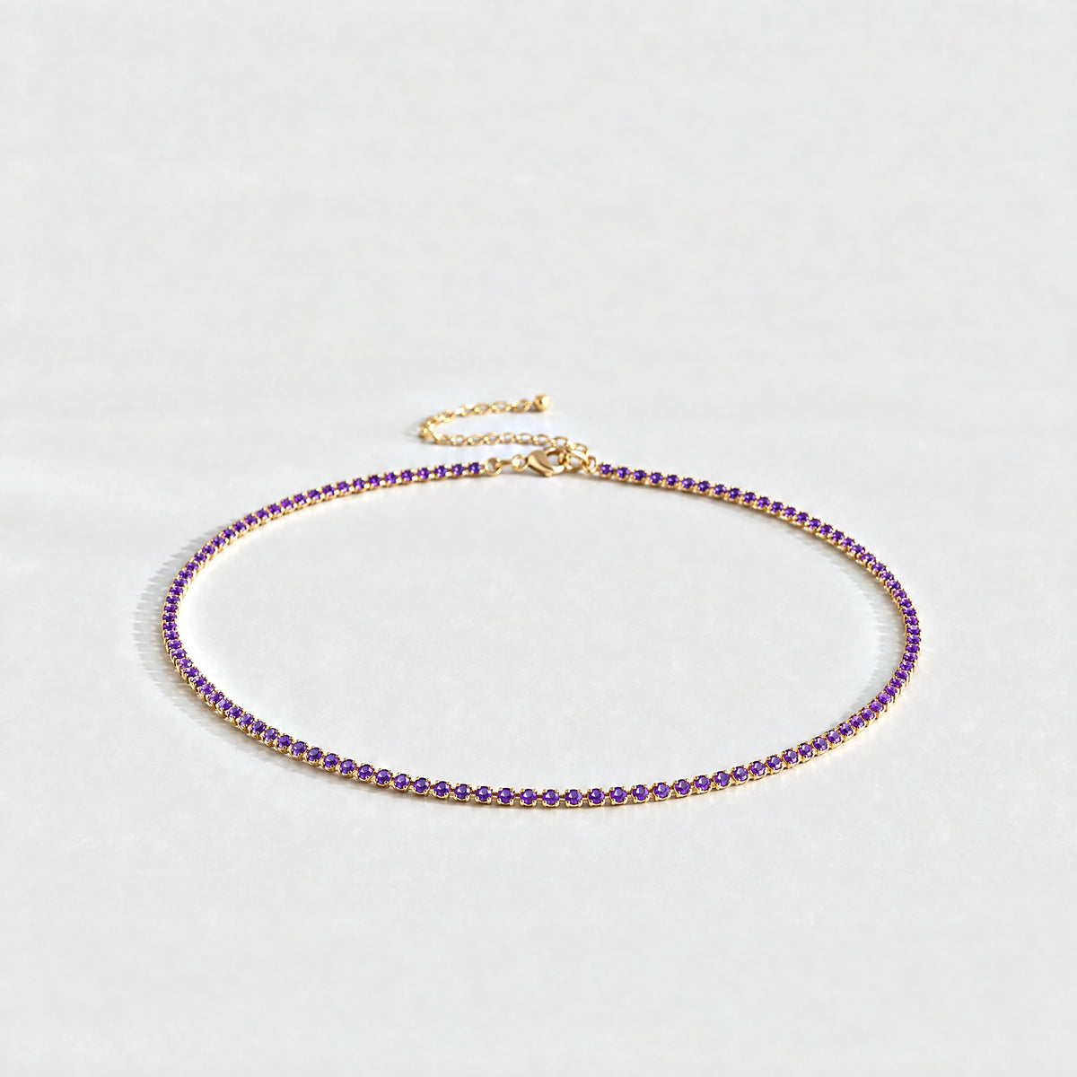 Gold Tessa Birthstone Tennis Necklace with amethyst violet February birthstone-color crystals on a light grey background