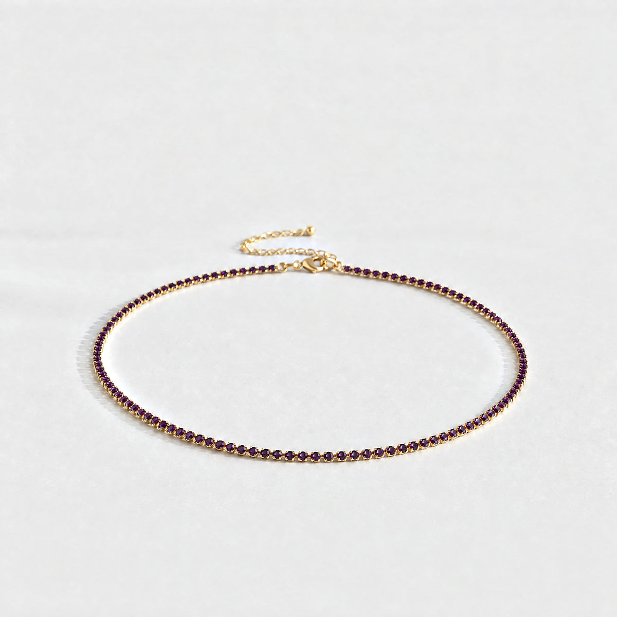Gold Tessa Birthstone Tennis Necklace with alexandrite plum June birthstone-color crystals on a light grey background