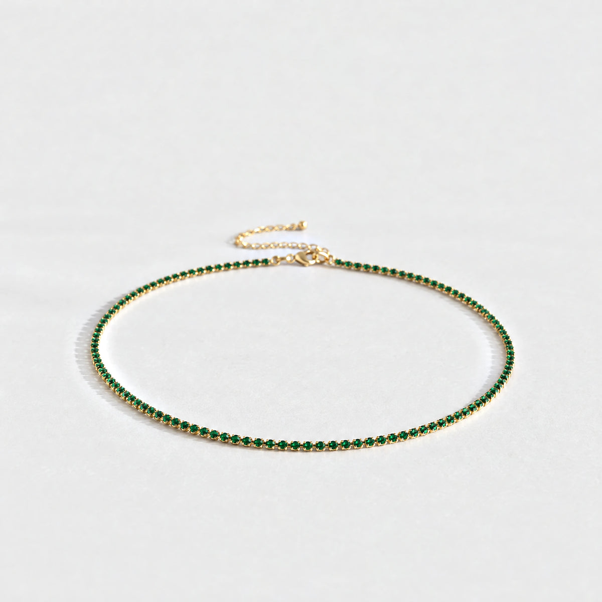 Gold Tessa Birthstone Tennis Necklace with emerald green May birthstone-color crystals on a light grey background