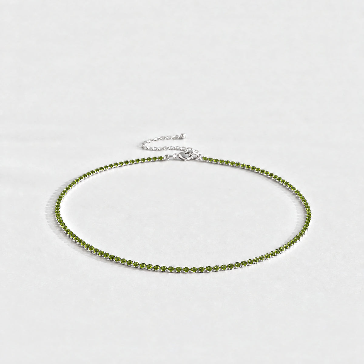 Silver Tessa Birthstone Tennis Necklace with peridot green August birthstone-color crystals on a light grey background