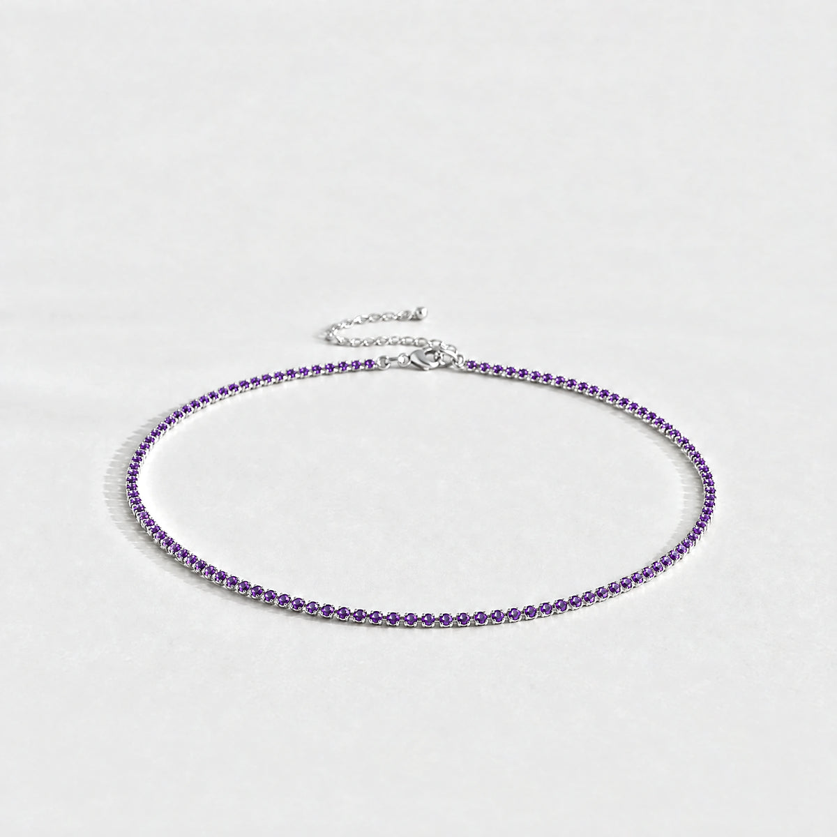 Silver Tessa Birthstone Tennis Necklace with amethyst violet February birthstone-color crystals on a light grey background