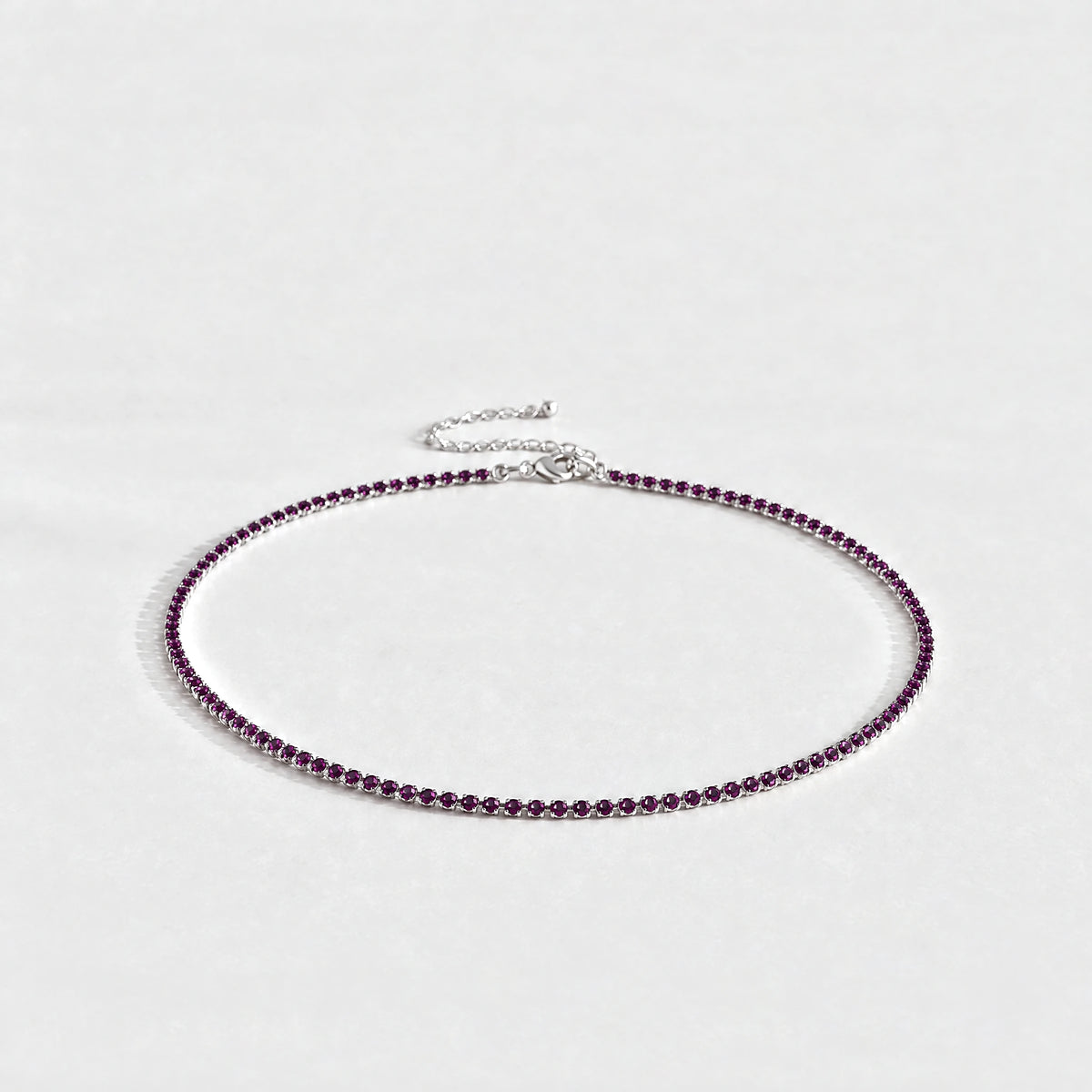 Silver Tessa Birthstone Tennis Necklace with alexandrite plum June birthstone-color crystals on a light grey background