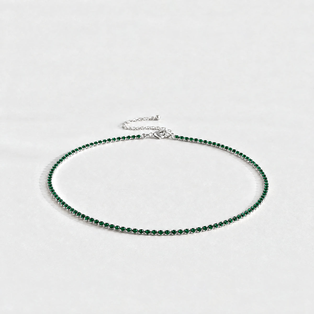 Silver Tessa Birthstone Tennis Necklace with emerald green May birthstone-color crystals on a light grey background