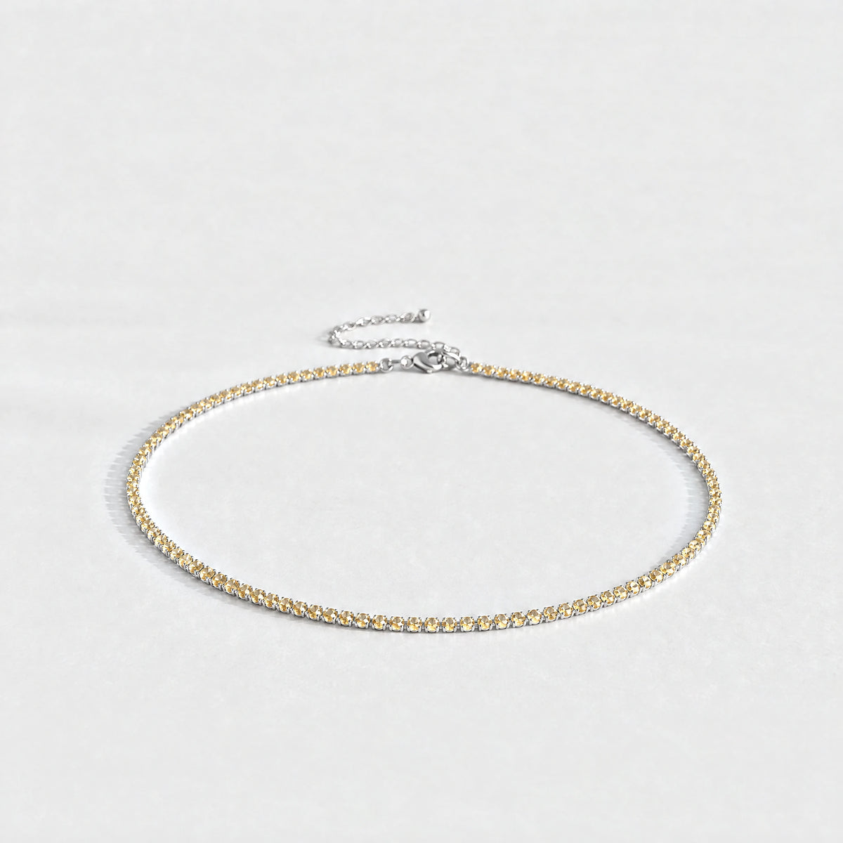 Silver Tessa Birthstone Tennis Necklace with citrine champagne November birthstone-color crystals on a light grey background