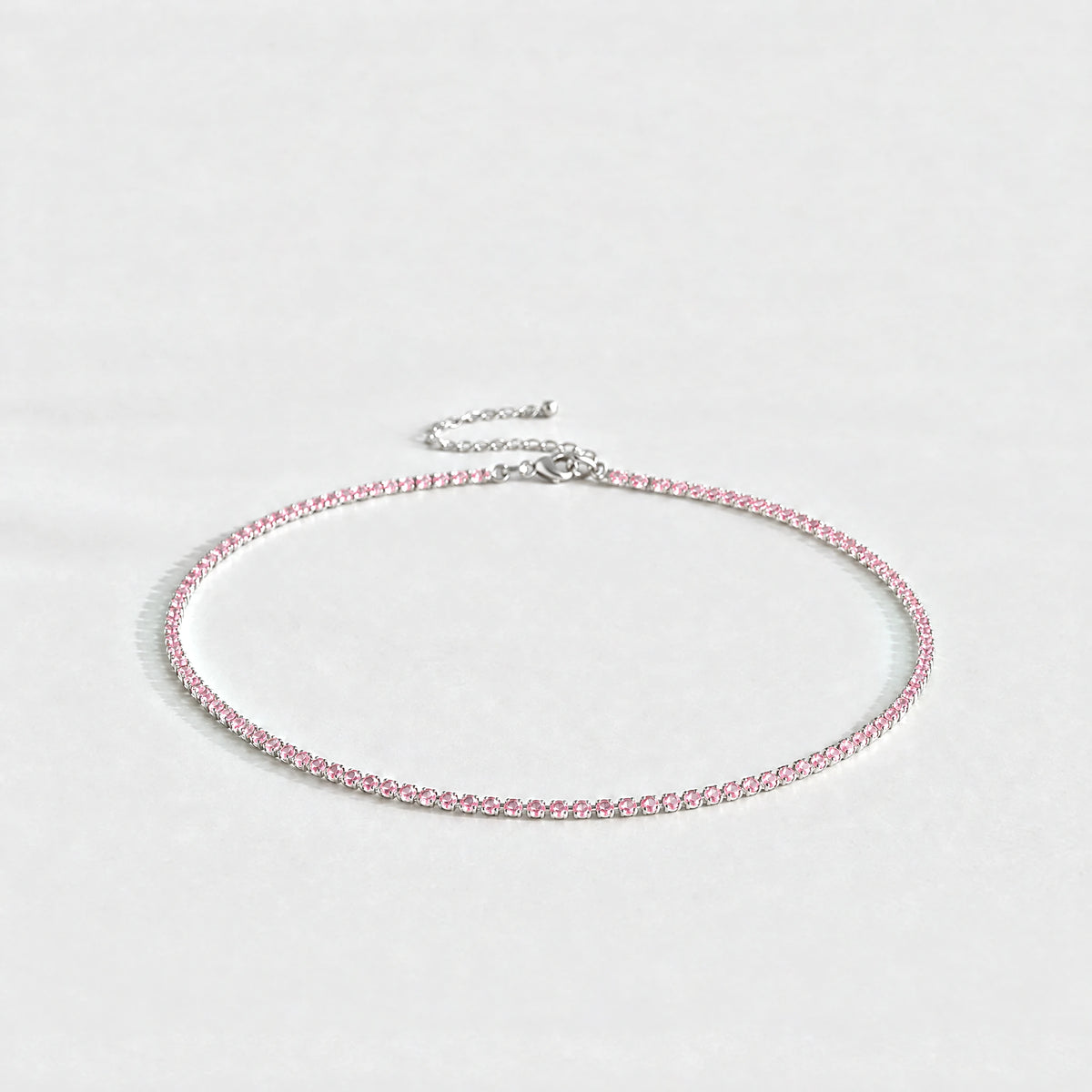 Silver Tessa Birthstone Tennis Necklace with tourmaline pink October birthstone-color crystals on a light grey background