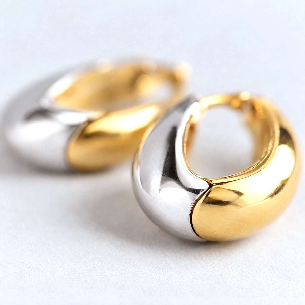 Close-up of the gold and silver halves of the Vera Two-Tone Oval Hoop Earrings