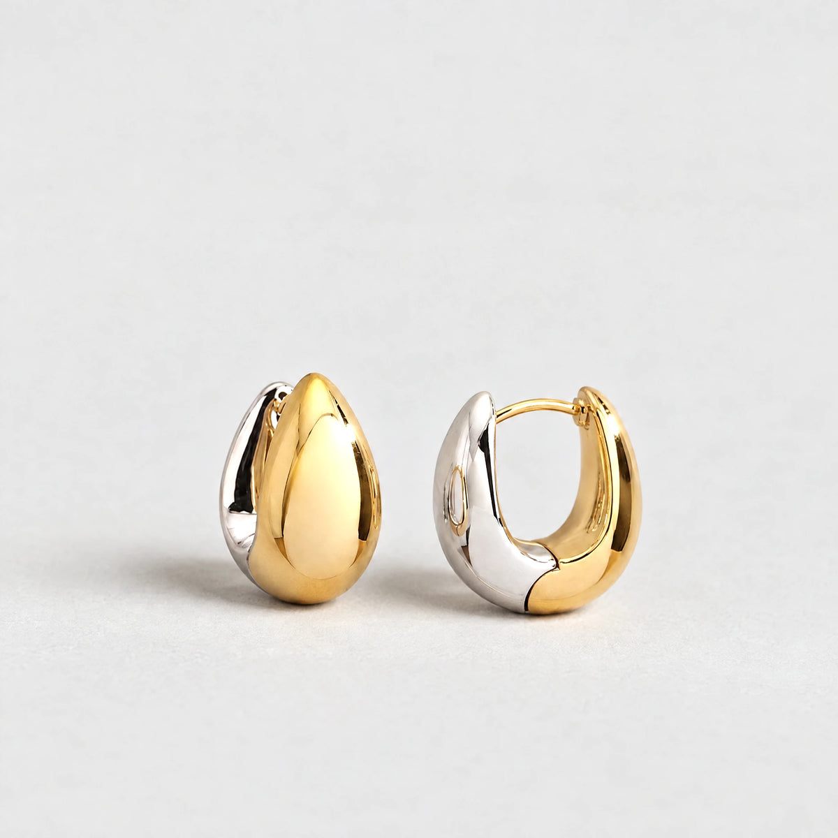 Vera Two-Tone Oval Hoop Earrings in gold and silver tones on a light grey background