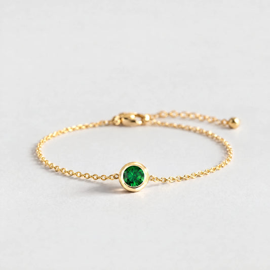 Gold Zara Birthstone Charm Bracelet with emerald green May birthstone-color crystal on a light grey background