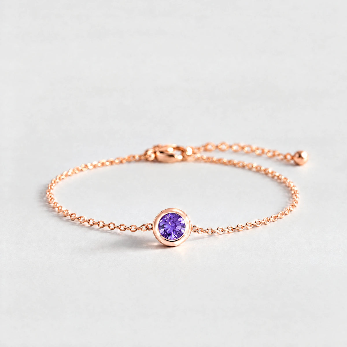 Rose gold Zara Birthstone Charm Bracelet with amethyst violet February birthstone-color crystal on a light grey background