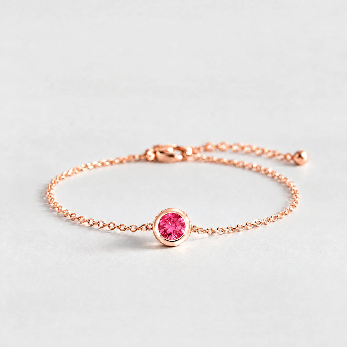 Rose gold Zara Birthstone Charm Bracelet with ruby rose July birthstone-color crystal on a light grey background