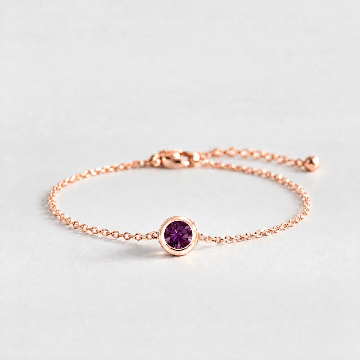 Rose gold Zara Birthstone Charm Bracelet with alexandrite plum June birthstone-color crystal on a light grey background