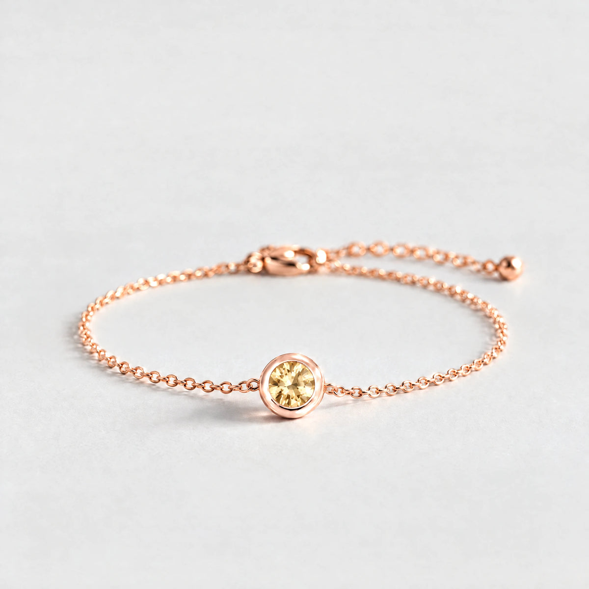 Rose gold Zara Birthstone Charm Bracelet with citrine champagne November birthstone-color crystal on a light grey background