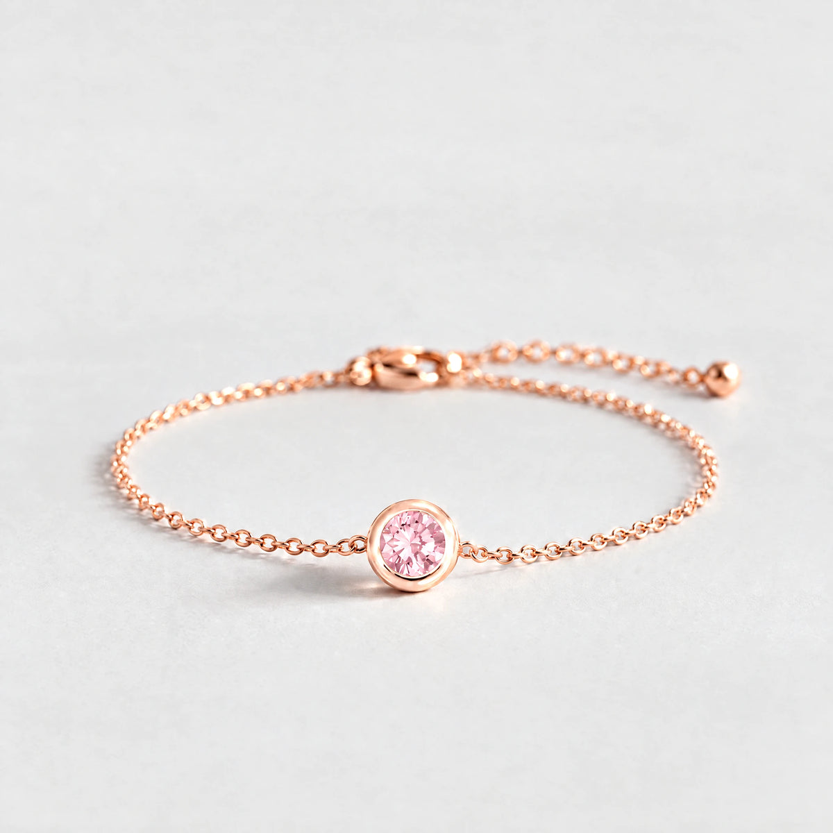 Rose gold Zara Birthstone Charm Bracelet with tourmaline pink October birthstone-color crystal on a light grey background